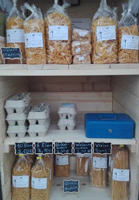 Foto: Ein Regal mit verschiedenen Nudelsorten und Eierkartons. Oben sind Weizennudeln, unten Dinkelnudeln und Eier. Preisschilder zeigen 10 Eier für 3,50€, 6 Eier für 2,10€, Dinkelnudeln für 3,30€ und Weizennudeln für 3,00€.